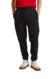 Black jogging pants with an elastic drawstring waist, silver-toned tips, side pockets, a light-colored logo on the left thigh