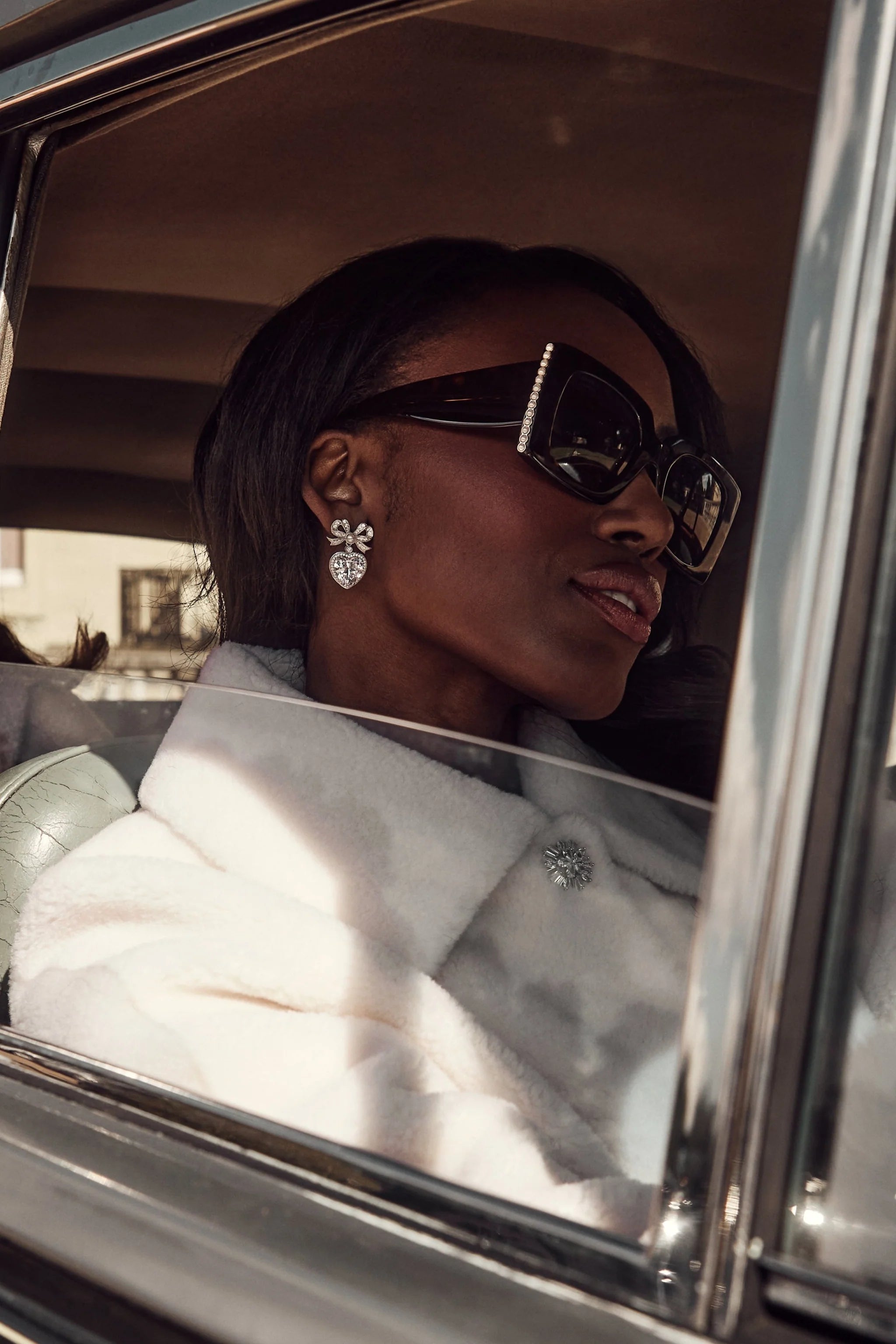 Silver-toned drop earring with a crystal-encrusted bow stud and a dangling crystal-encrusted heart.
