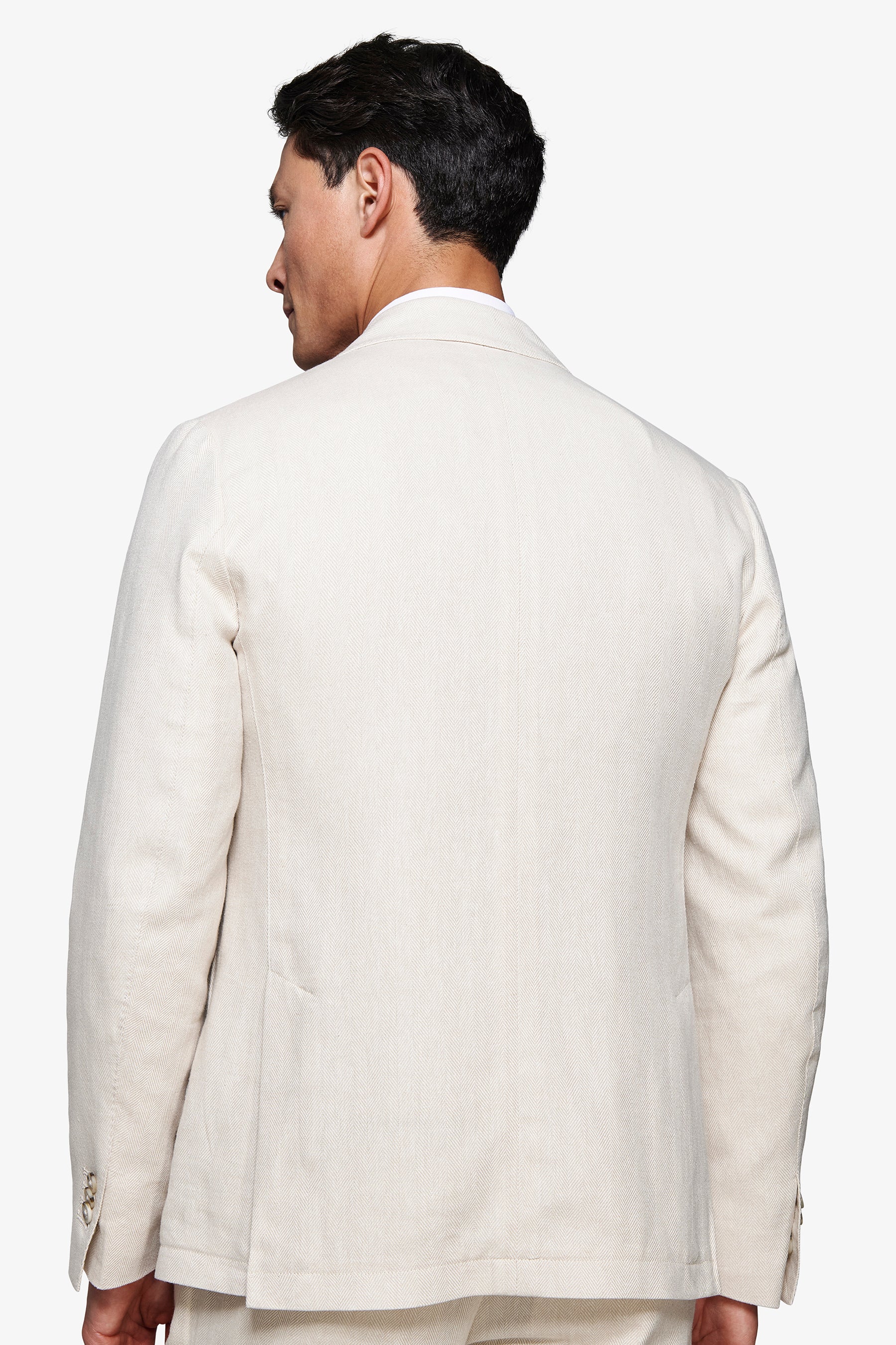 Sabbia modular jacket, back view. Features a subtle textured weave and three light-toned buttons on the left sleeve cuff.