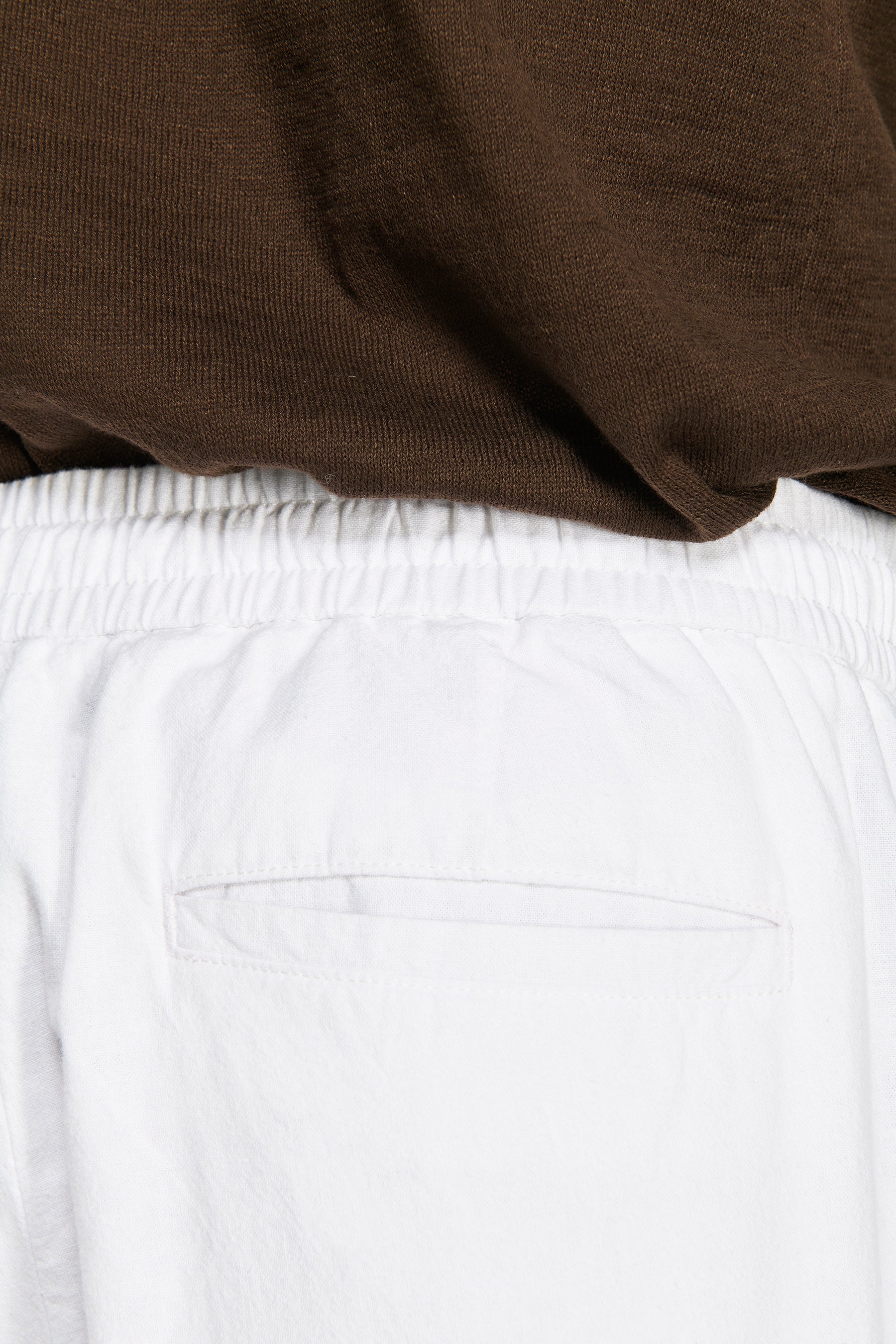 White linen blend trousers with an elasticated drawstring waist and a single horizontal welt back pocket.
