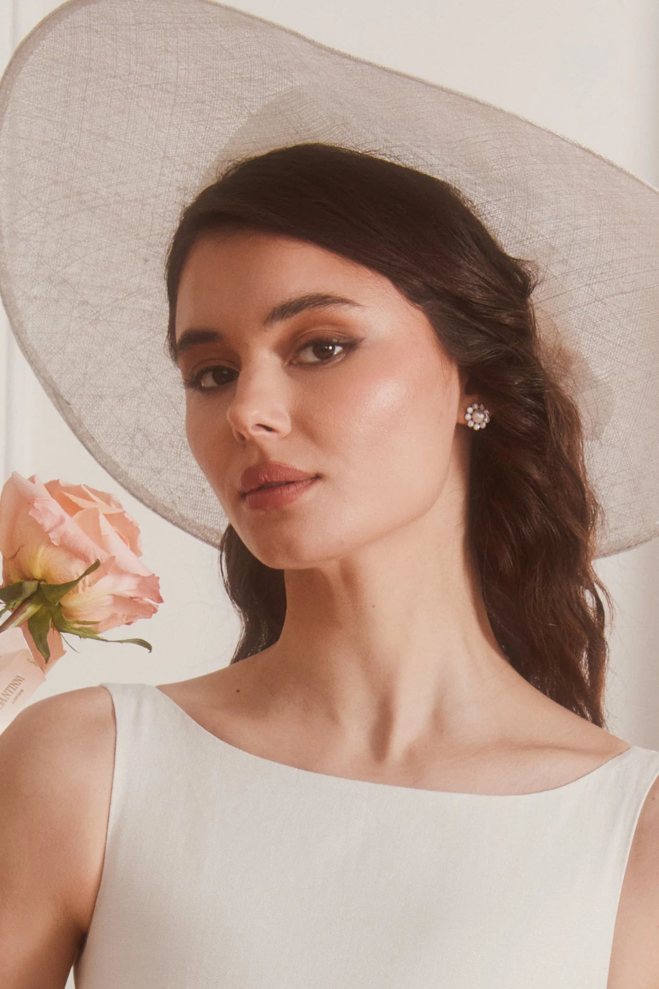 A single silver-toned stud earring with a central white freshwater pearl surrounded by clear stones in a flower design.