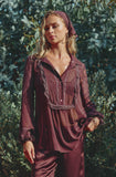 Deep plum pyjama set: sheer collared button-down top with lace trim, pintucks, and ruffled cuffs; paired with satin pants.