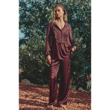 Brown silky pyjama set with a long-sleeved sheer top featuring lace trim, pintucks, and a button front, paired with wide-leg