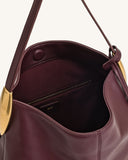 Burgundy faux leather hobo bag with a thin shoulder strap, gold-toned curved metal charm, and an interior zip pocket.