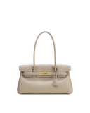 Light beige structured shoulder bag with a single top handle, flap closure, gold-toned turn-lock clasp, and a small hanging t