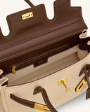 Cream shoulder bag with dark brown trim, straps, and white contrast stitching. Gold-toned turn-lock closure with key, interio