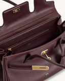 Deep burgundy structured faux leather shoulder bag with gold-toned rectangular clasp, key detail, and interior zipper pocket.