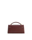 Deep burgundy top handle bag with white contrast stitching, gold-toned hardware, and two buckle-like closures on the front.