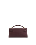 Deep burgundy textured top handle bag with a structured flap closure, gold-toned hardware, and two D-ring style loops.