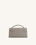 Grey textured faux leather top-handle bag with a single handle, gold-toned hardware, and two strap-like tabs on the front fla