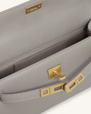 Grey pebbled faux leather top handle bag with an open gold-toned turn-lock closure. Light stitching and interior pocket visib