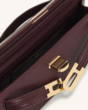 Burgundy structured top-handle handbag with a smooth finish, gold-toned ribbed push-lock closure, and dark interior.