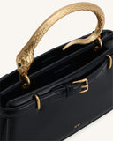 Black structured top handle bag with a gold-toned snake handle featuring green eyes. It has two black straps with gold-toned