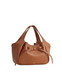 Dark brown pebbled faux leather soft tote bag with two top handles and a tied bow detail on the front.