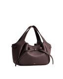 Dark brown pebbled faux leather tote bag with two handles, a gathered top, and a soft bow detail on the front. Gold-toned log