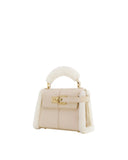 Taupe faux suede top handle bag with cream shearling trim on sides and handle, and a gold-toned turn-lock clasp.