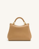 Tan faux leather top handle bag with a structured shape and a single rounded handle attached by gold-toned loops.