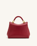 Red faux leather top handle bag with a rounded handle and gold-toned hardware.
