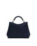 Navy blue faux suede top handle bag with a curved top edge and a dark, curved handle attached by silver-toned rings.