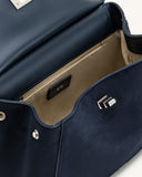 Open navy faux suede bag with light tan interior lining. Features a gold-toned zipper pocket, silver-toned side studs, and a
