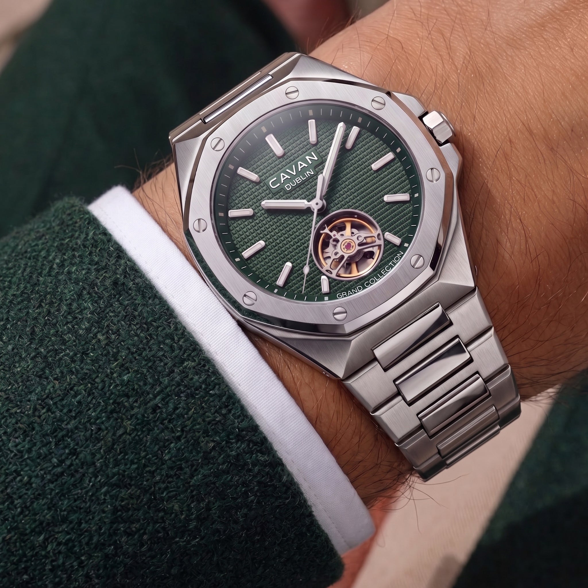 Silver-toned octagonal watch with a textured dark green dial, visible gold-toned gears, and a silver-toned metal bracelet.