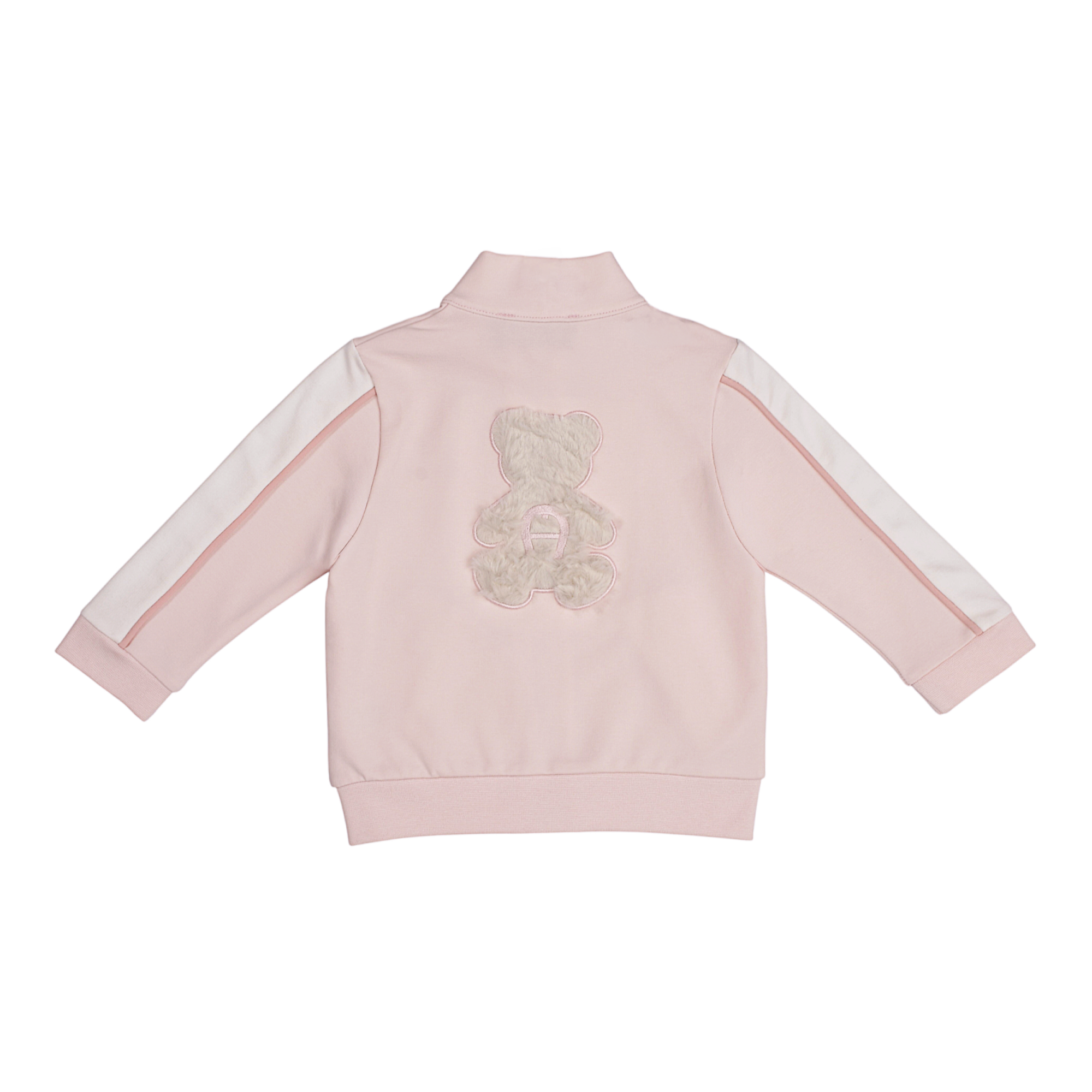 Pink jogging jacket with stand-up collar, white and pink sleeve stripes, and a fluffy light grey teddy bear appliqué on the b