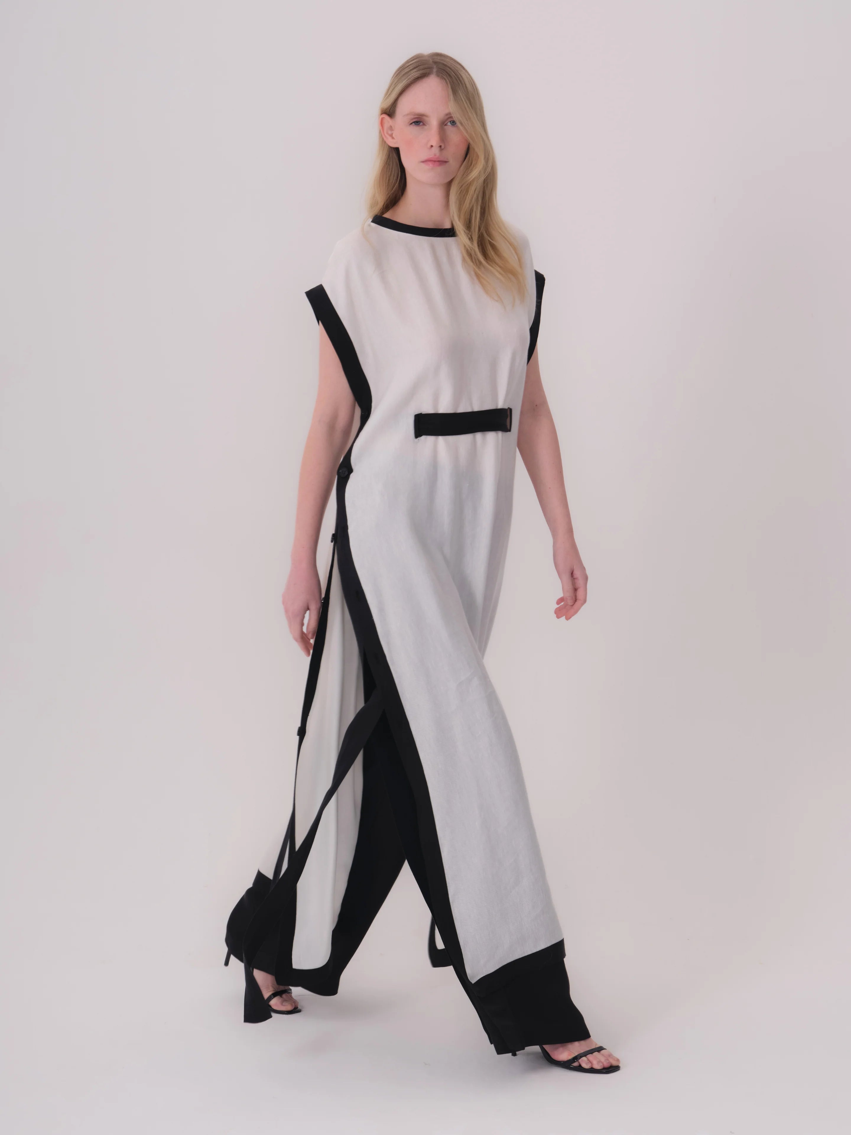 White long dress with black trim on round neck, cap sleeves, and hem. Features a black horizontal band at the waist and long