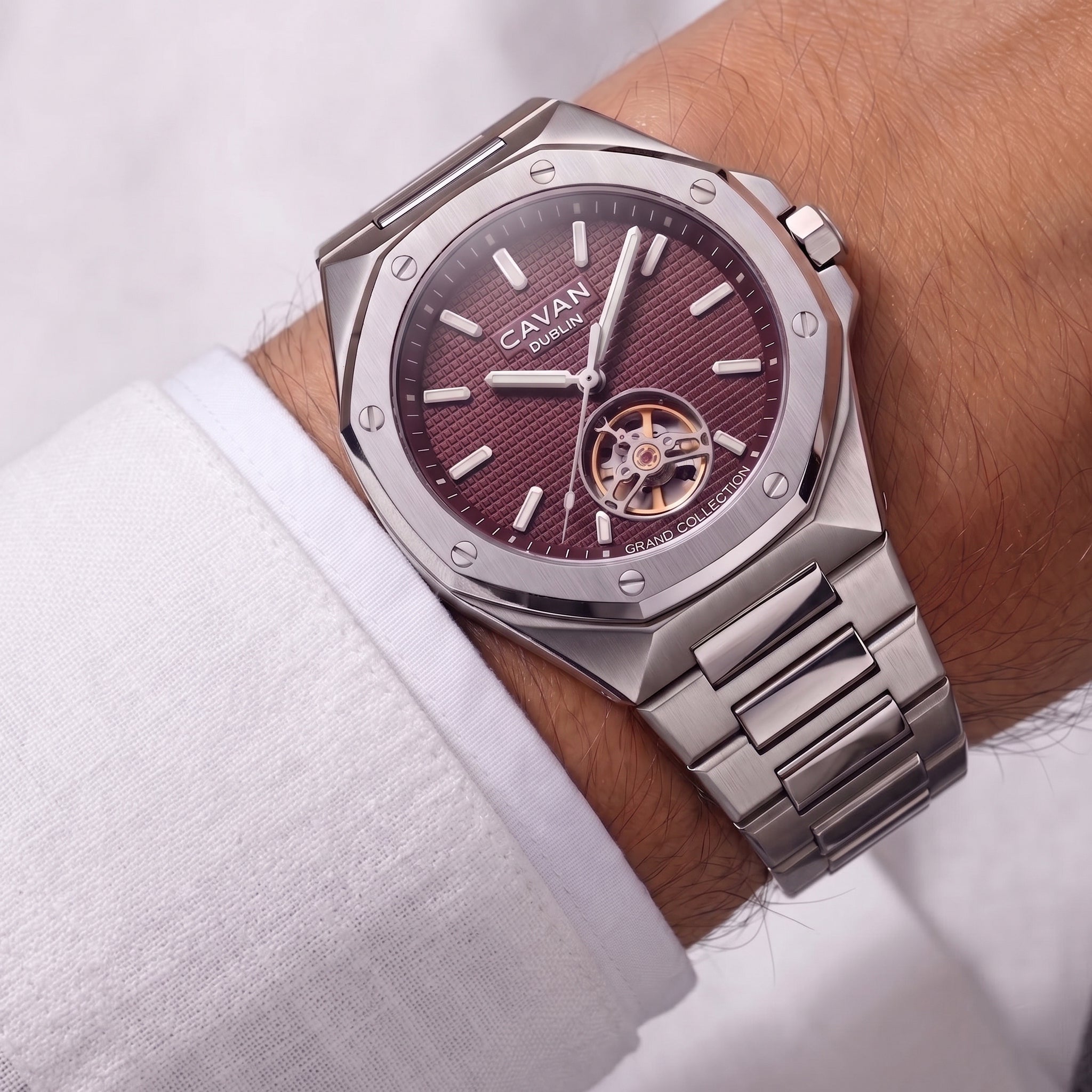 Silver-toned octagonal watch with a textured burgundy dial, silver-toned markers, open-heart movement with gold-toned gears,