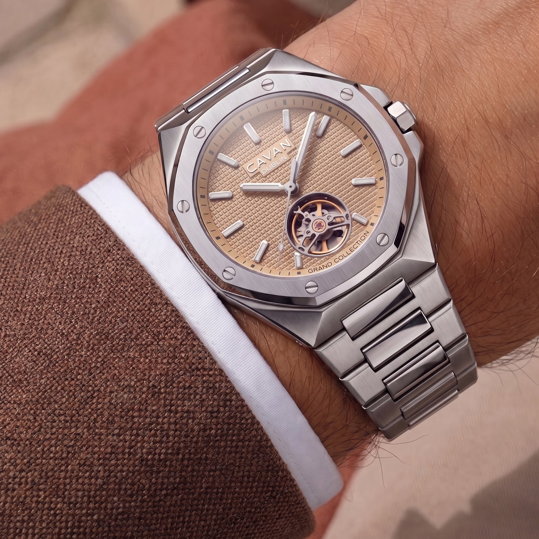 Silver-toned faceted watch with a gold-toned textured dial, visible gold-toned gears at 6 o'clock, and a silver-toned metal l