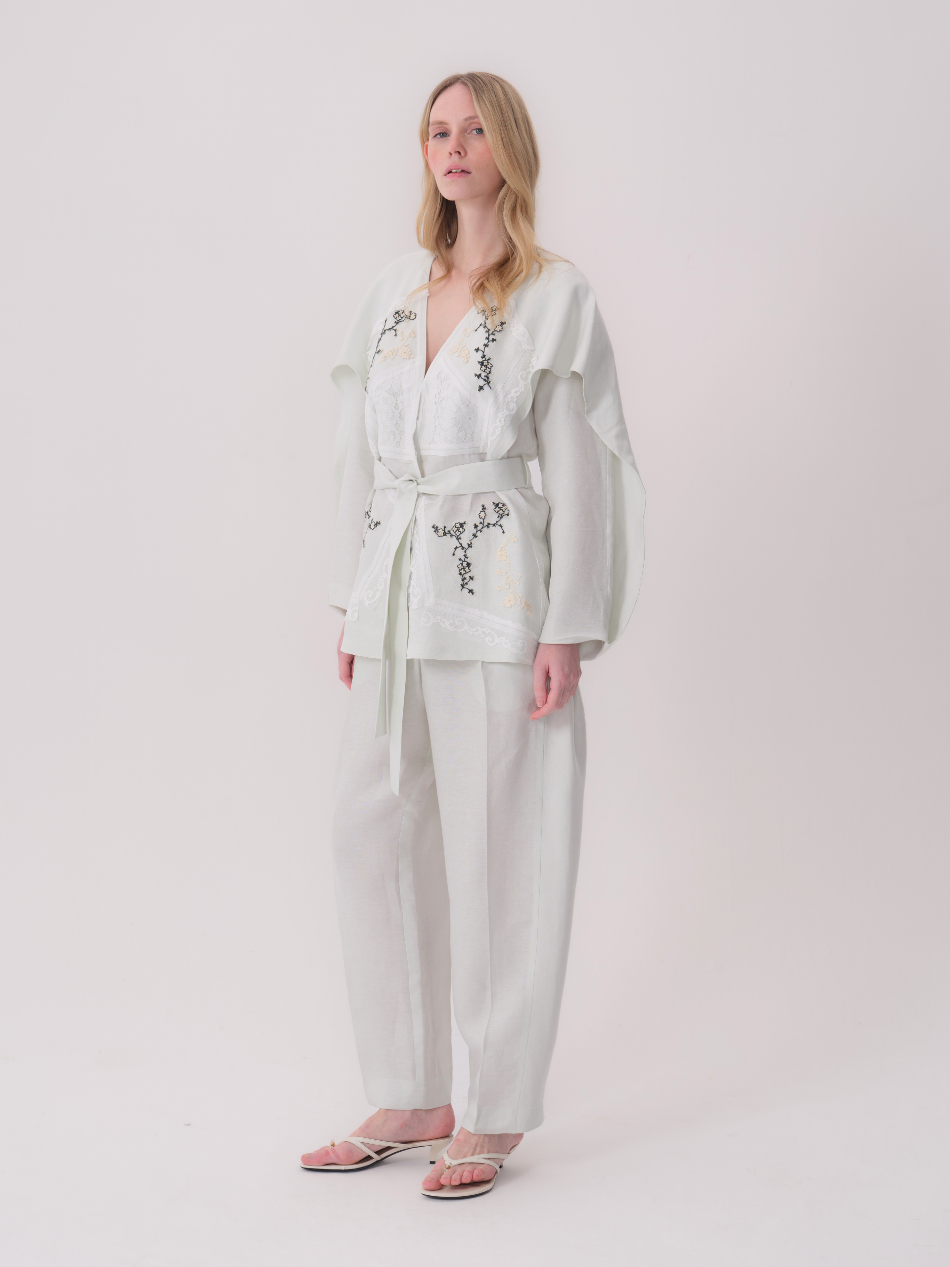 Mint green kimono jacket with a V-neck, wide sleeves, self-tie belt, and black and cream floral embroidery on the front.
