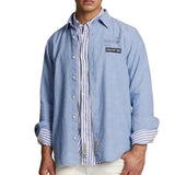 Light blue long-sleeve button-down shirt with white buttons. Rolled cuffs reveal blue/white striped lining. 'LA MARTINA' and