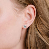 A single silver-toned stud earring featuring a round, clear faceted stone secured by four prongs.