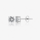 Pair of silver-toned stud earrings, each with a round, brilliant-cut clear stone in a 4-prong setting. One shows its post and