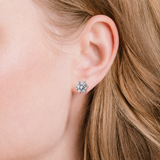 Round, clear, faceted stone stud earring with a silver-toned six-prong setting.