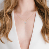 Gold-toned chain necklace with a square, clear stone pendant in a four-prong gold-toned setting.