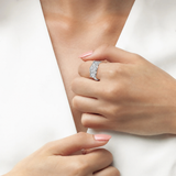 Silver-toned ring with three clear, round-cut stones across the top, the center stone slightly larger.