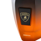 Ombre perfume bottle, grey to orange, with a black plaque featuring a gold-toned Lamborghini shield logo and "FIEREZZA" text.