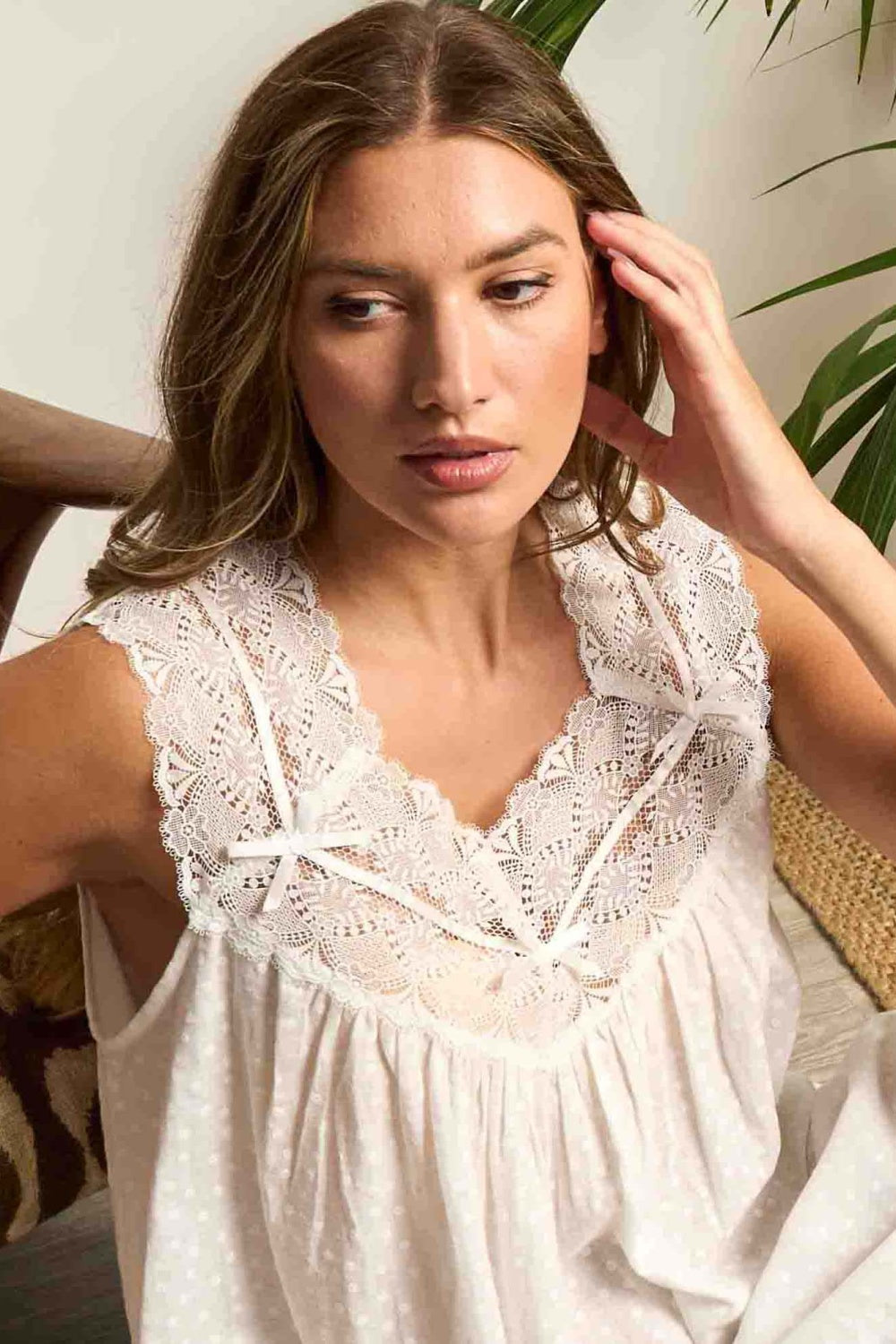 Cream dress with white scalloped lace V-neck and shoulder straps, featuring two small white bows. Main fabric has an embossed