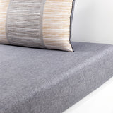 Grey flat sheet with a rectangular pillow featuring horizontal grey, white, and gold-toned stripes, separated by vertical ban