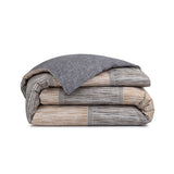 Folded reversible duvet cover. One side solid dark grey; the other has horizontal brown, beige, white, and dark grey stripes