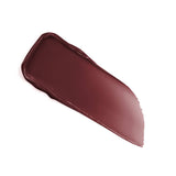 Glossy dark reddish-brown lip product swatch, with a thick, creamy texture, tapering to a feathered edge.