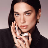 Two cylindrical lip gloss tubes with silver-toned caps and bases. One is shimmery light pink, the other darker pink. Silver-t