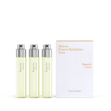 Three clear glass fragrance vials with light yellow liquid and silver-toned spray tops, next to a white and orange branded bo