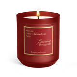 Deep red frosted glass scented candle with a white wax interior and a lit wick, featuring a gold-bordered label.