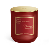 Deep red cylindrical candle in a glass jar with a gold-toned lid. A red label with gold text 'Maison Francis Kurkdjian Paris