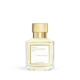 Clear glass perfume bottle with pale yellow liquid and a gold-toned square cap, featuring a white label with black text.