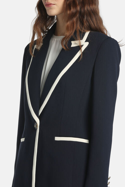 Navy blue jacket with off-white trim on notched lapels, front opening, and two slit pockets. Features a single dark button wi