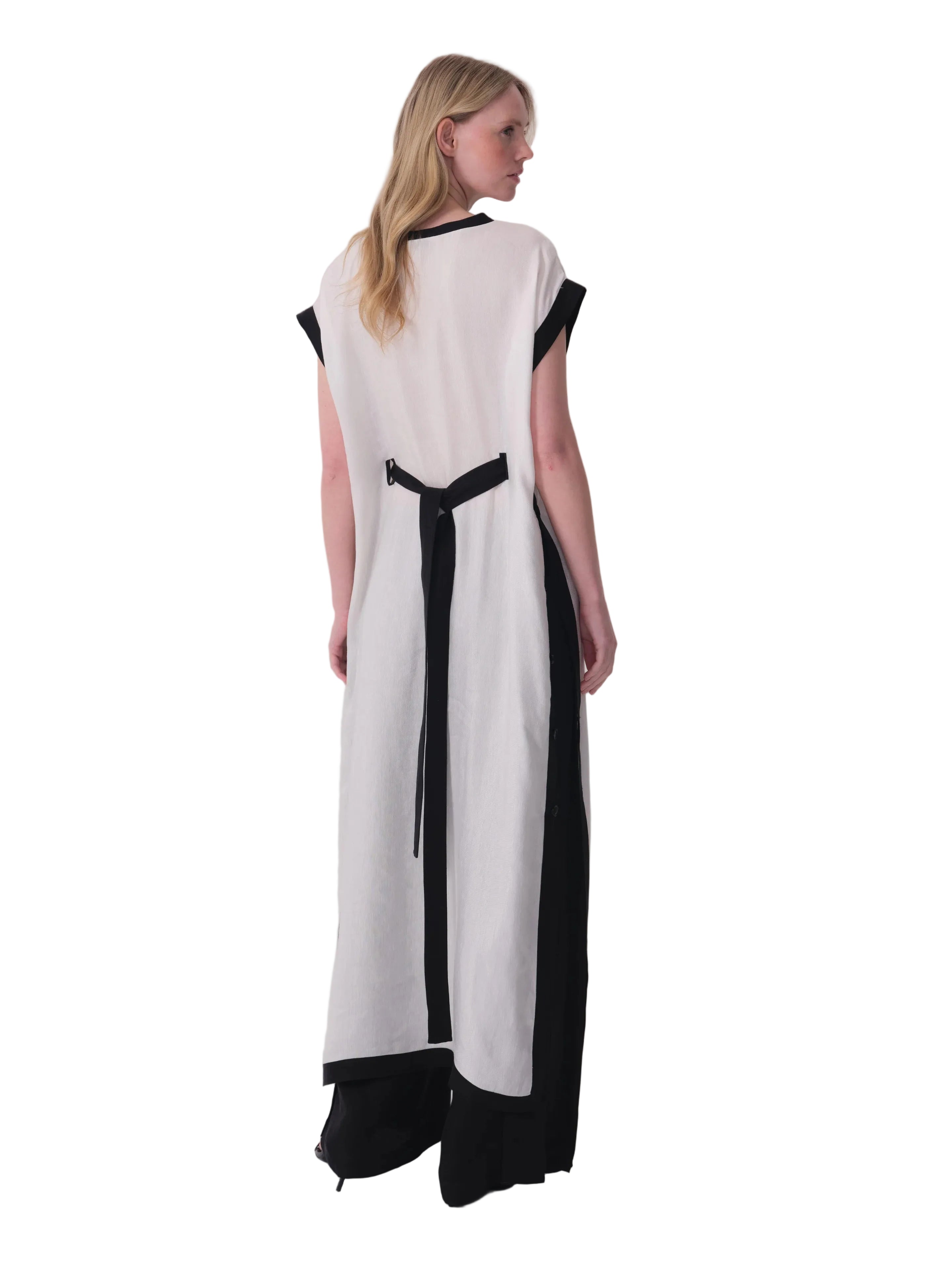 Long white dress with black trim on the round neck and cap sleeves, featuring a black tie-back and black vertical side panels