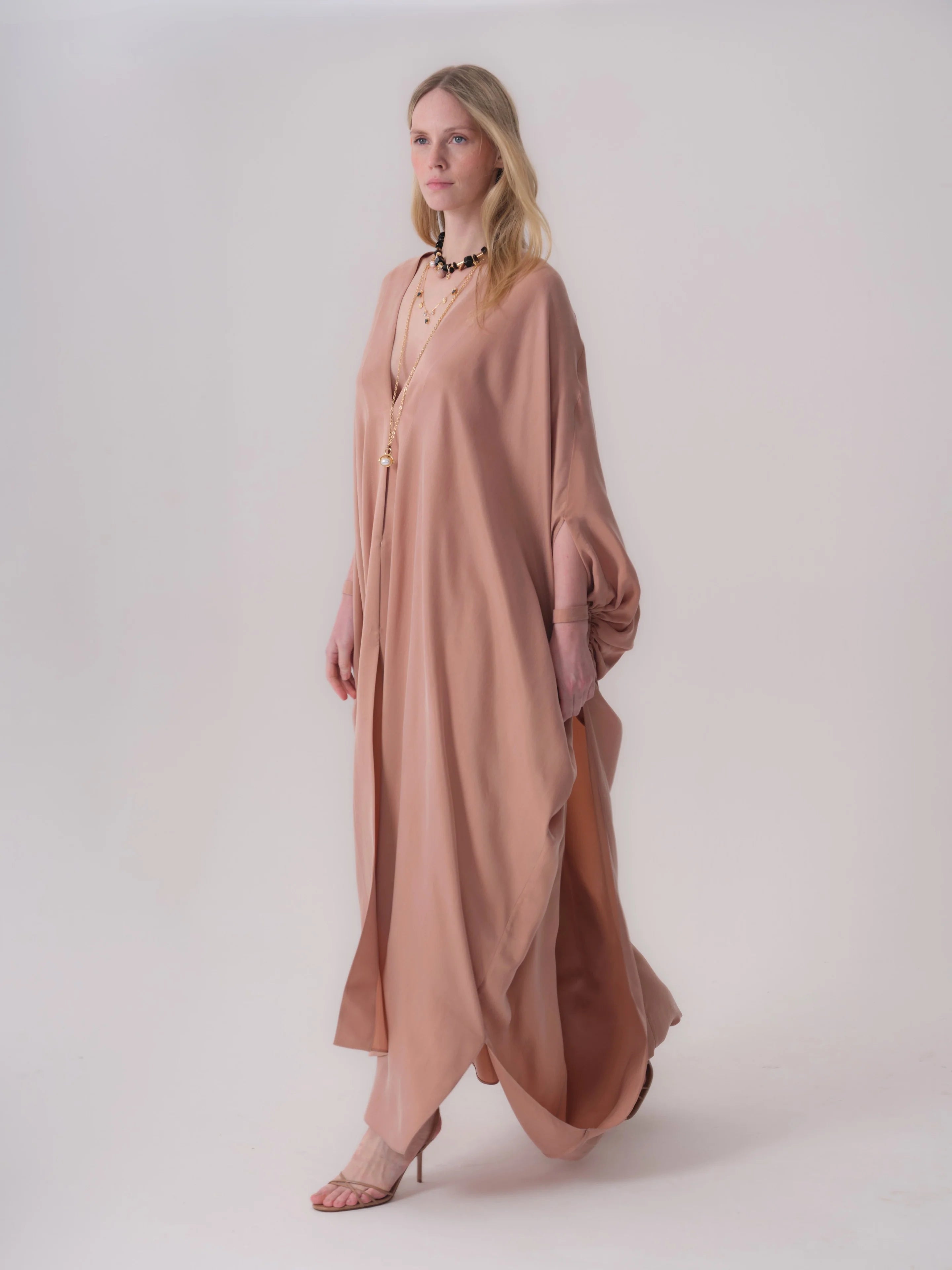 Dark beige flowing abaya with a deep V-neck, wide dolman sleeves gathered at the wrist, and side slits.