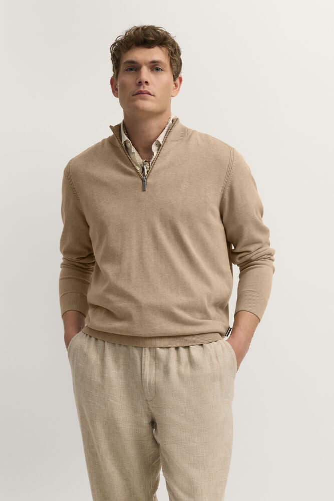 Beige quarter-zip sweater with a ribbed collar, cuffs, and hem. It has a dark grey-toned zipper pull.